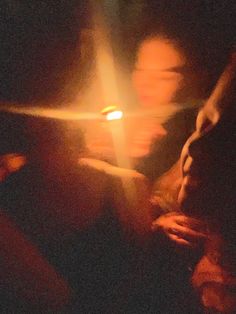 two people sitting next to each other with a lit candle in the dark behind them