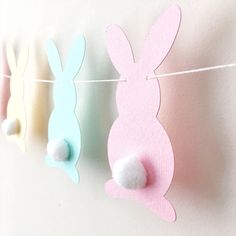 three bunnies hanging on a clothes line with cotton balls