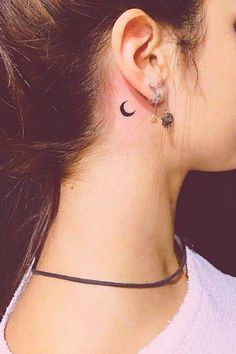 a woman with a small crescent tattoo on her left side behind the ear is wearing a black choker