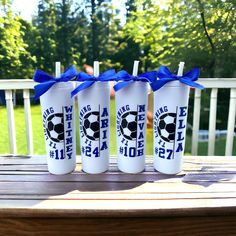 three white tumblers with blue bows are sitting on a table