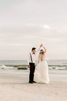 a bride and groom dancing on the beach