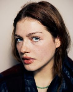 a close up of a person with blue eyes and a leather jacket on, looking at the camera