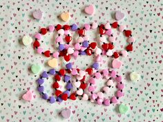 many different colored hearts are scattered on a white surface with pink, red, and green shapes