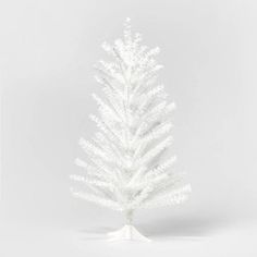 a white christmas tree is shown on a stand in front of a plain background with space for text