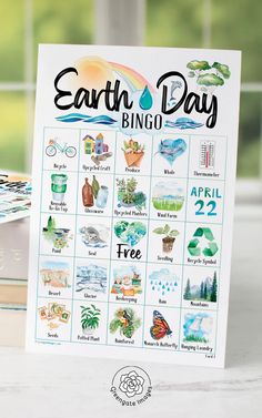 the earth day bingo game is sitting on top of a table next to some books