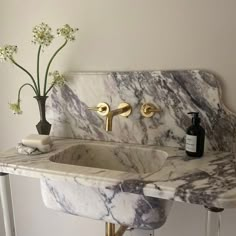 a marble sink with two faucets and a bottle of soap next to it