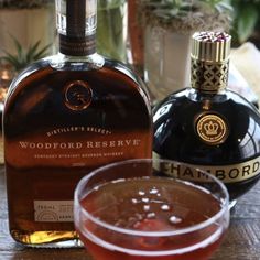 a bottle of woodford reserve sitting next to a glass filled with liquid on a table