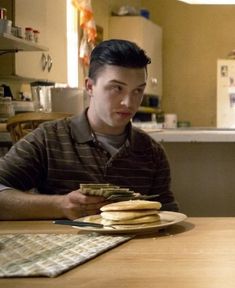 a man sitting at a table with some pancakes in front of him