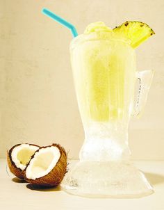 a drink in a blender next to a half eaten coconut