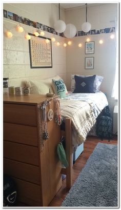 a bedroom with a bed, dresser and rugs on the wooden floor next to a window