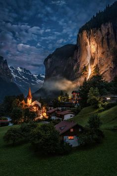 a village in the mountains at night with lights shining down on it's buildings