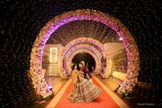 the bride and groom are walking down the aisle at their wedding reception in an archway decorated with flowers