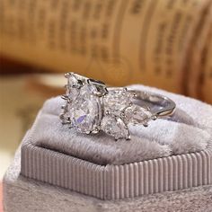 three stone diamond ring sitting on top of a velvet box with its lid open to show it's reflection