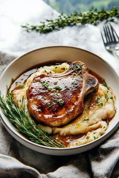 a white plate topped with meat and potatoes covered in gravy next to a fork