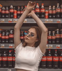 a woman wearing sunglasses standing in front of a display of sodas