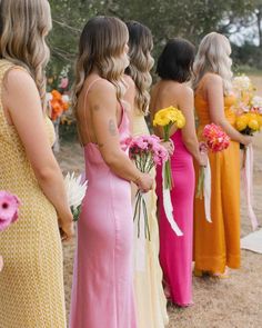 a group of women standing next to each other holding bouquets in their hands and looking at each other