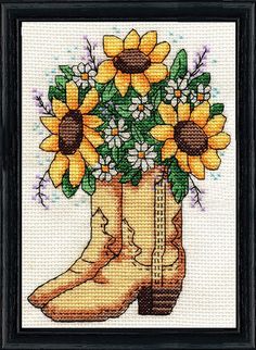 a cross stitch picture with sunflowers in a cowboy boot