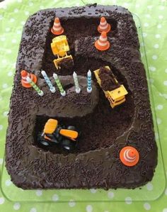 there is a chocolate cake with construction trucks on the top and candles in the middle