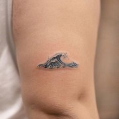 a small wave tattoo on the back of a woman's left arm