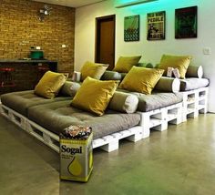 a room with couches made out of pallets and some yellow pillows on them