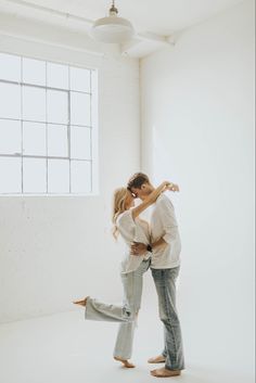 a man and woman standing in an empty room with their arms around each other as they hug