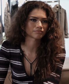 a woman with long curly hair sitting down