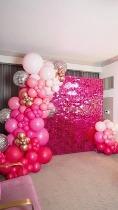 pink and gold balloons are hanging from the ceiling in front of a large mirror wall