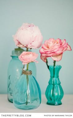 three vases with flowers in them sitting on a table