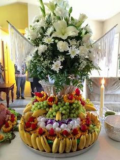 a table topped with lots of different types of fruits and vegetables next to a vase filled with flowers