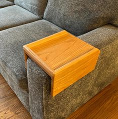 a close up of a couch with a wooden end table on the armrests