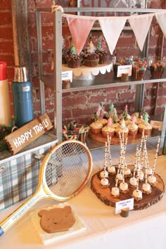 a table topped with cupcakes and cakes next to a racket filled with tennis racquets