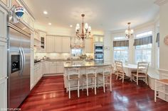 a large kitchen with white cabinets and wooden floors