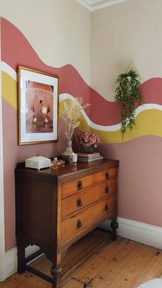 a room with a dresser and painting on the wall