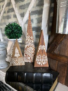 three wooden trees sitting on top of a book next to a vase with flowers in it