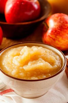 a bowl filled with pudding next to some apples