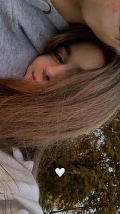 a girl with long brown hair and a white heart on her neck is looking at the camera