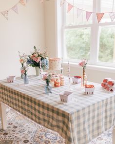 a table topped with lots of cakes and cupcakes next to a large window