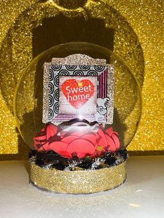 there is a snow globe with candy in it on the table next to a gold glitter wall