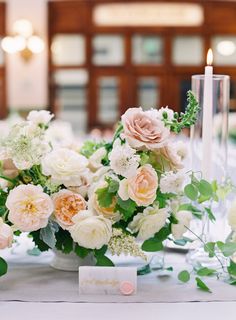 an arrangement of flowers and greenery is displayed on a table at a wedding reception