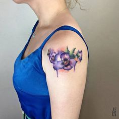 a woman wearing a blue dress has a purple flower tattoo on her left upper arm