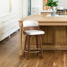 a kitchen with white cabinets and wooden counter tops, along with a bar stool that has an upholstered seat