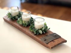 candles are placed on a wooden tray with succulents