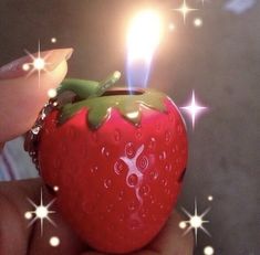 a person holding a strawberry shaped lighter with sparkles on the top and bottom side