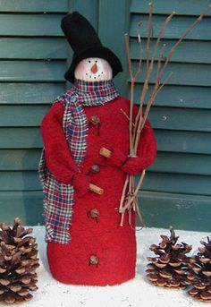 a snowman made out of a red coat and hat with pine cones on the ground