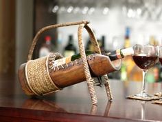 a wooden wine bottle holder sitting on top of a table next to two glasses of wine