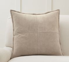 a beige pillow sitting on top of a white couch