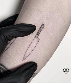 a knife tattoo on the thigh with black gloves and gloves next to it's leg