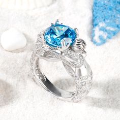 Unique and shimmering, this beautiful mermaid ring adds out-of-this-world sparkle to your style. Beautifully handcrafted in fine sterling silver, this stunning design showcases a sparkling aquamarine color stone at the center, while coral-shaped prongs add more glamour to the design.Glistening with detail, a lifelike mermaid shimmers with more stones, completing ring's distinctive shank. A heart cut stone sparkles between its beautiful tail, expressing all the love you hold in your heart.Carat Weight: 6.2 ctStone Size: 10 mmStone Type: Jeulia® StoneNumber of Stones: 1 Stone Color: Aquamarine BlueStone Shape: RoundCarat Weight: 1.574 ctStone Size: 0.8,1,1.1,1.3,1.5,3*3 mmStone Type: Jeulia® StoneNumber of Stones: 145 Stone Color: Diamond WhiteStone Shape: Round, HeartWeight: 10 gWidth: 12.5 Luxury Light Blue Rings For Women, Luxury Ocean-inspired Rings For Gift, Amethyst Mermaid Ring, Aquamarine Mermaid, Couples Vintage, Memorable Jewelry, Goddess Of The Sea, Princess Gifts, Mermaid Ring