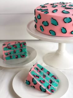 a cake with blue and pink frosting sitting on top of a white plate next to another cake