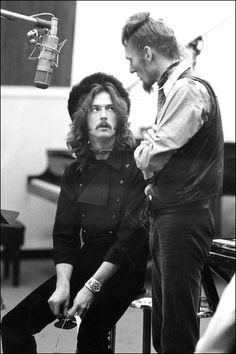 two men sitting next to each other in front of a microphone and recording equipment,